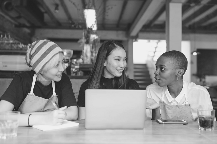 three individuals sitting at a table with a laptop